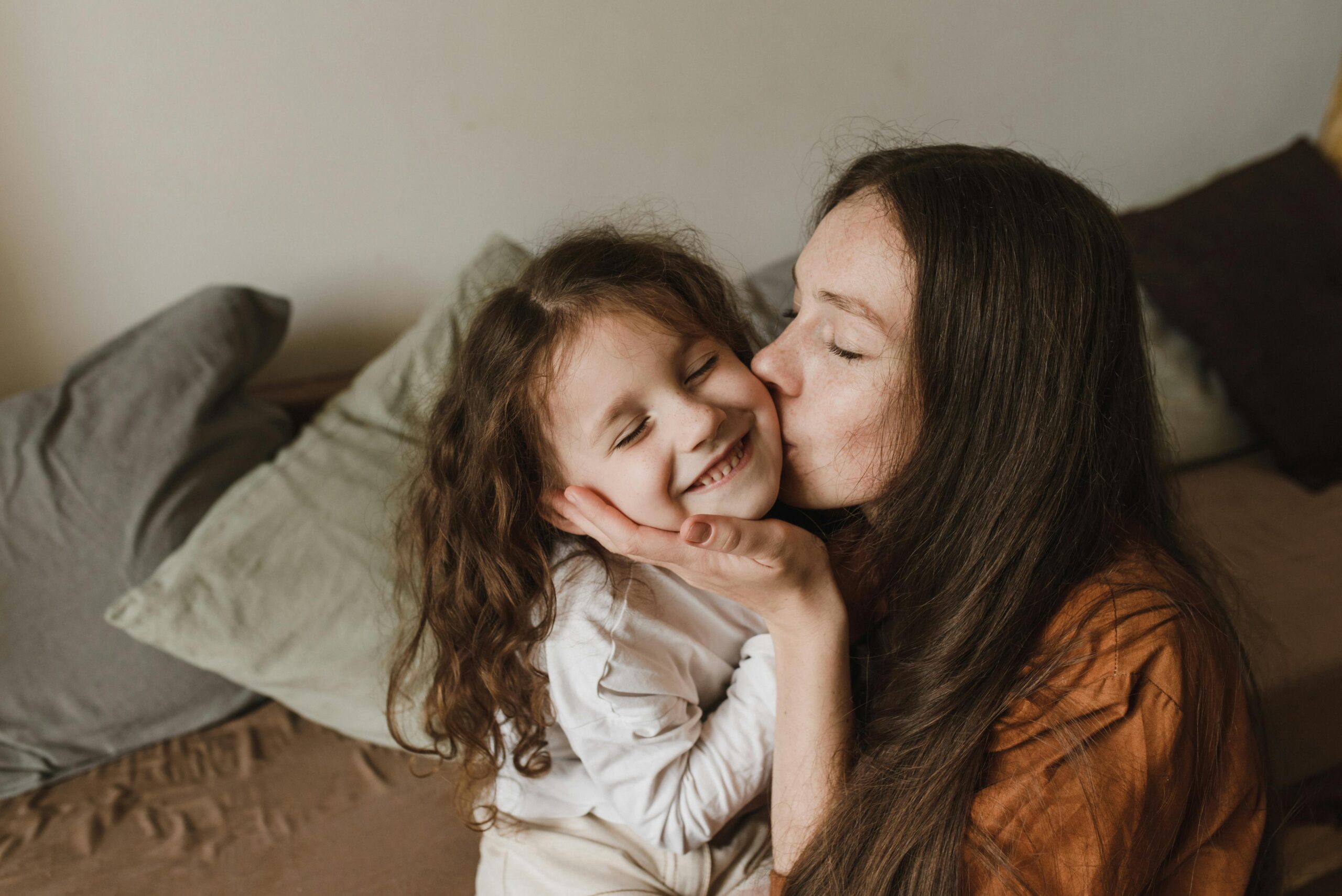 A mother kisses her child on the cheek